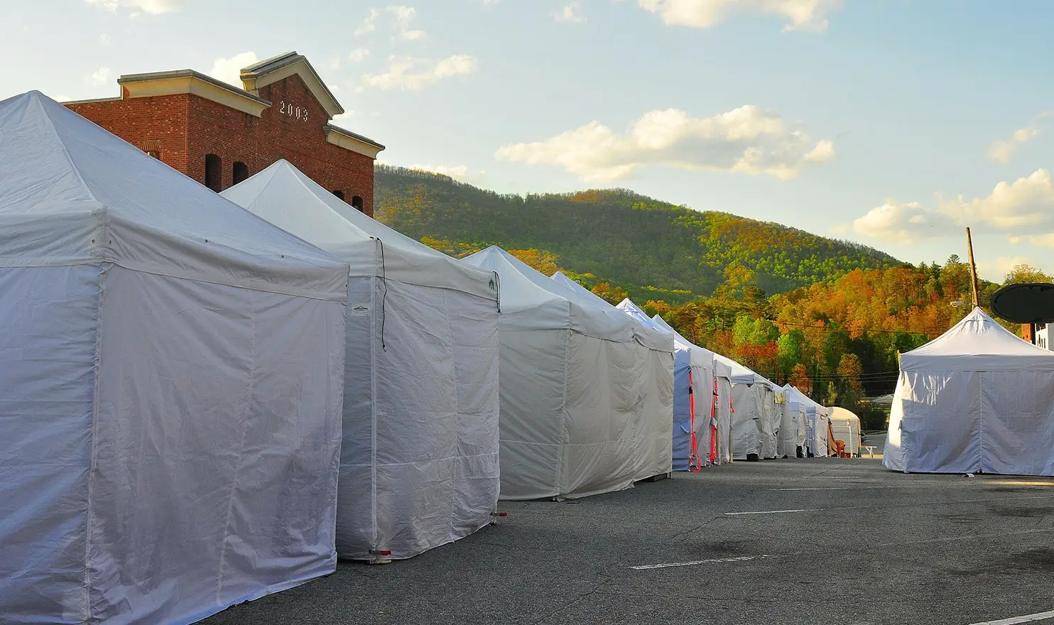 A row of white vendor booth tents at an outdoor craft market.
