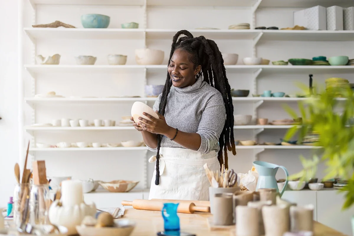 A potter works with a smile in a clean pottery studio.