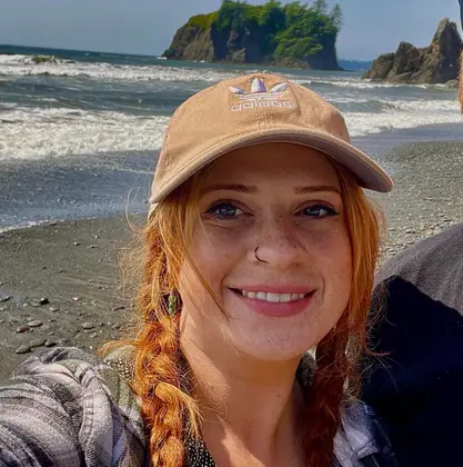 Alyssa Walker of Frog Mustard wearing a beige baseball cap at the beach.